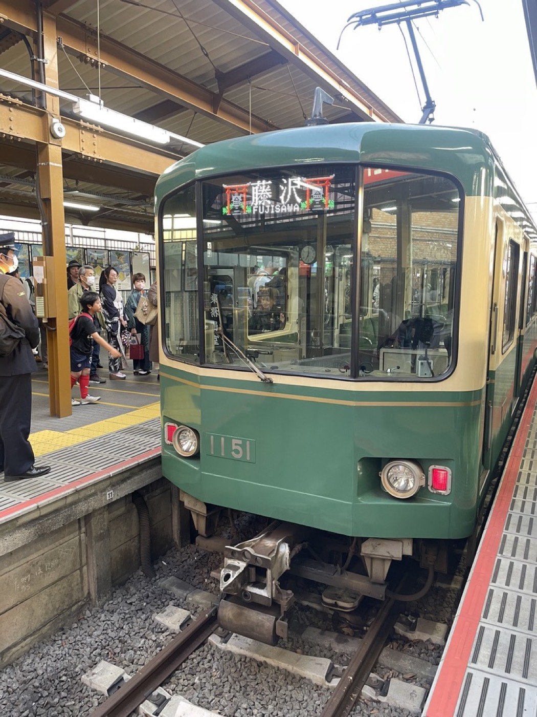 The little green Enoden tram-train waiting at a platform in Kamakura