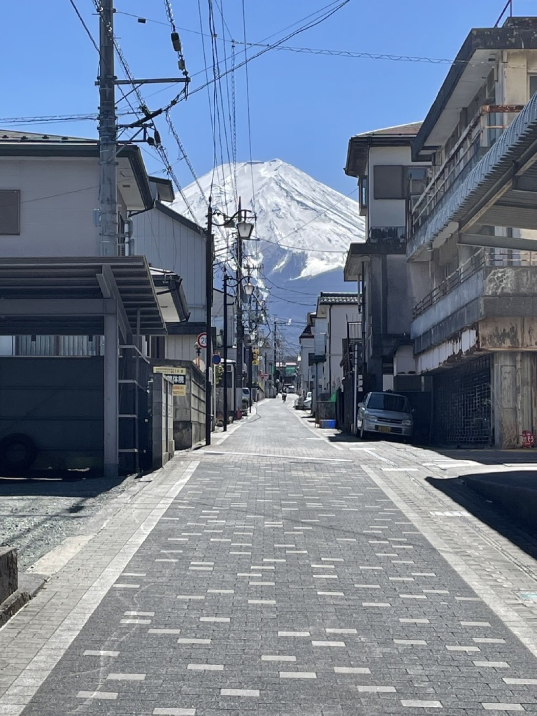 A quiet Fujiyoshida street with snow-capped Mt Fuji towering at its end