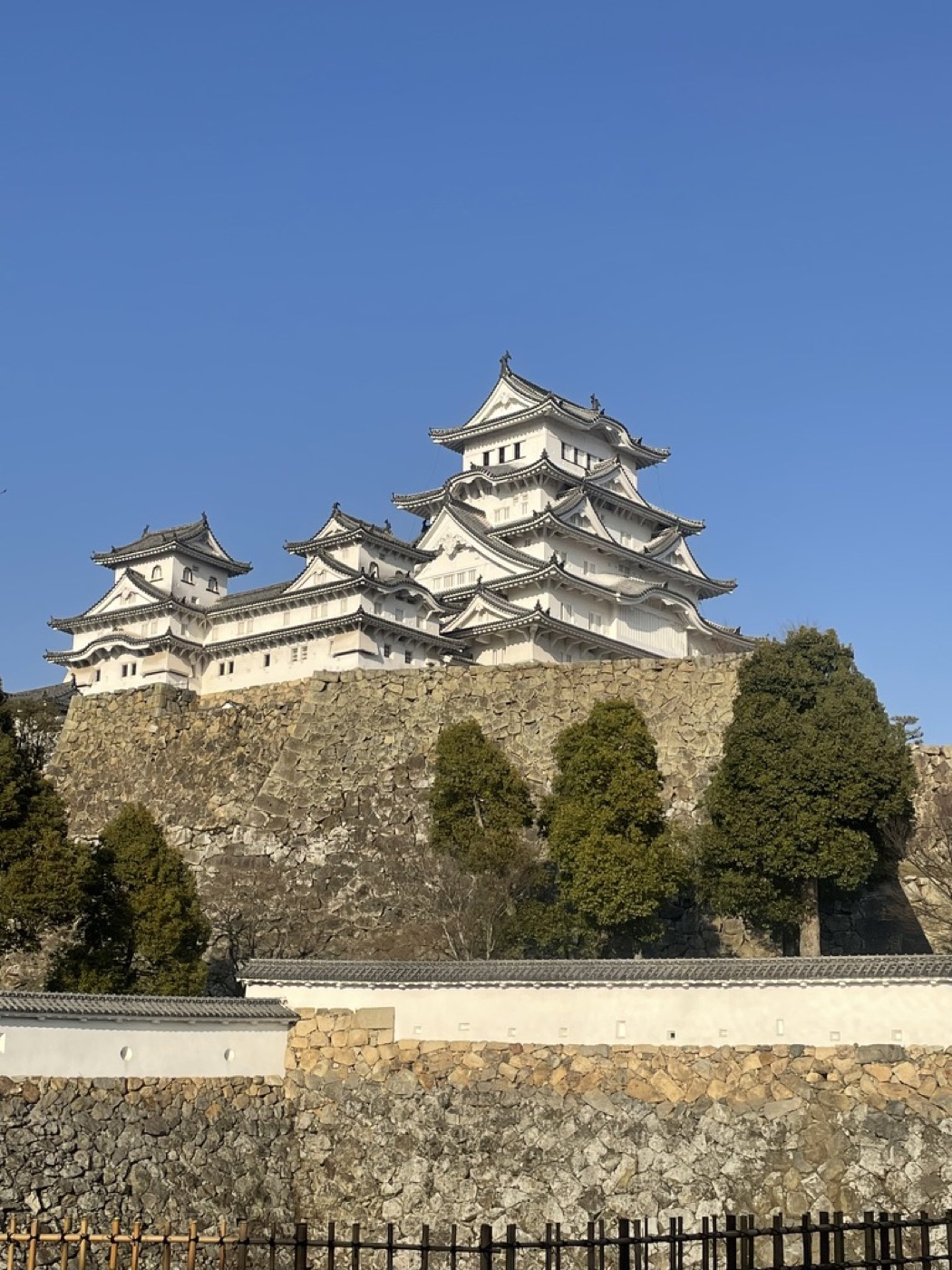 Himeji Castle's white keep rising above stone walls and trees